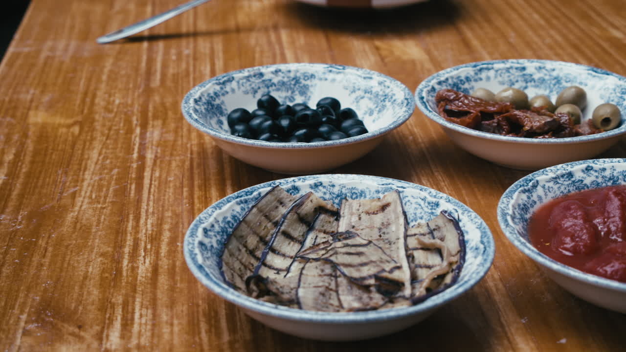 el chef pone platos con ingredientes de pizza en la mesa de madera