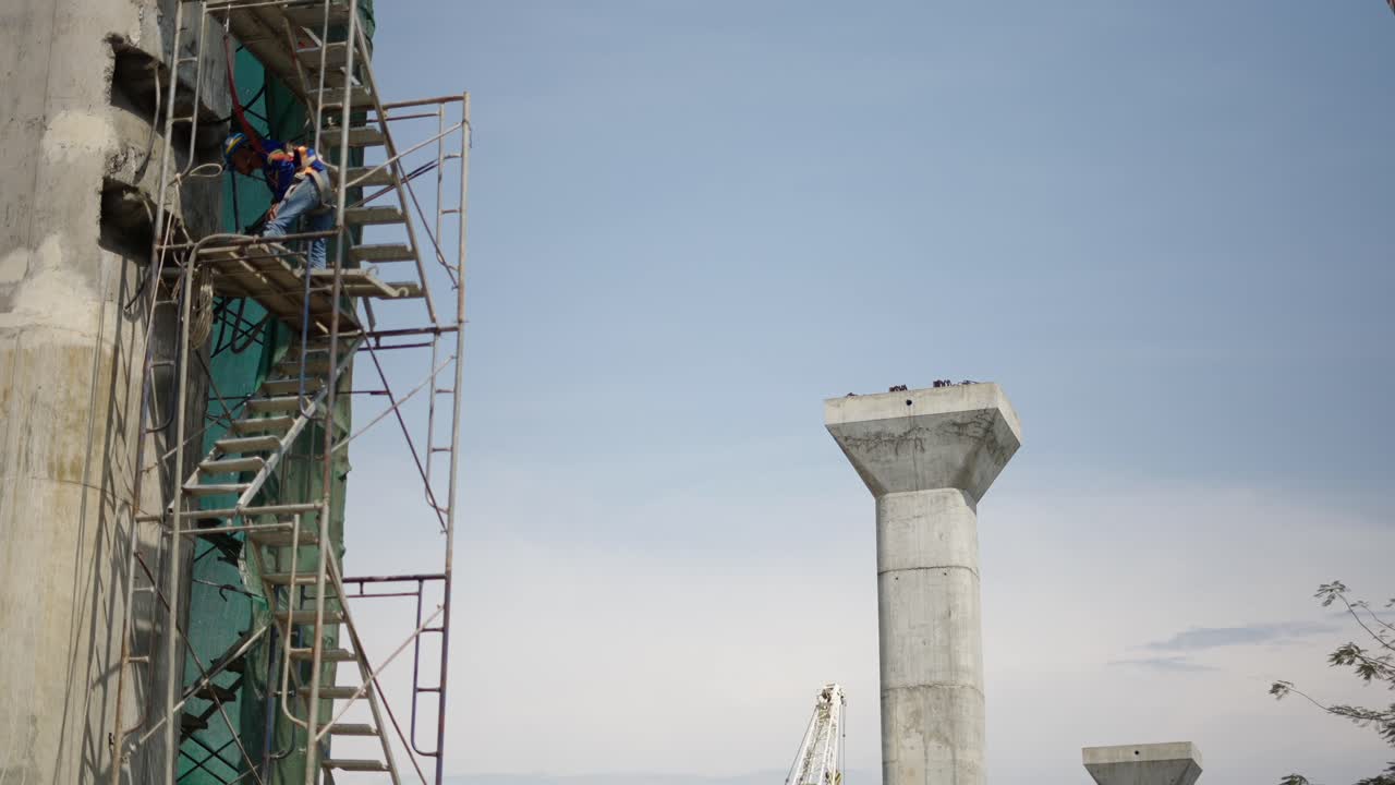 Construction site with workers on scaffolding and concrete pillars