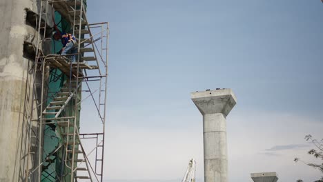construction site with workers on scaffolding and concrete pillars