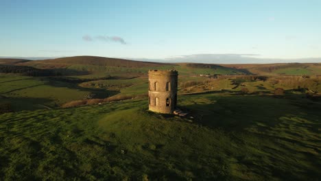 historischer steinturm auf einem grasbewachsenen hügel