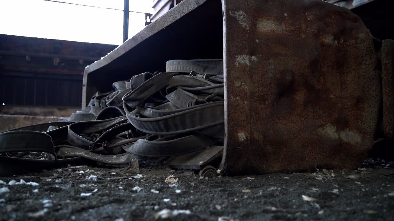 Old rusty iron cole wagon filled with straps lies at the ground of abandoned grunge eerie factory