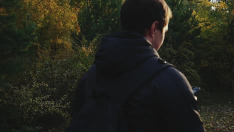 man hiking and using phone in a forest