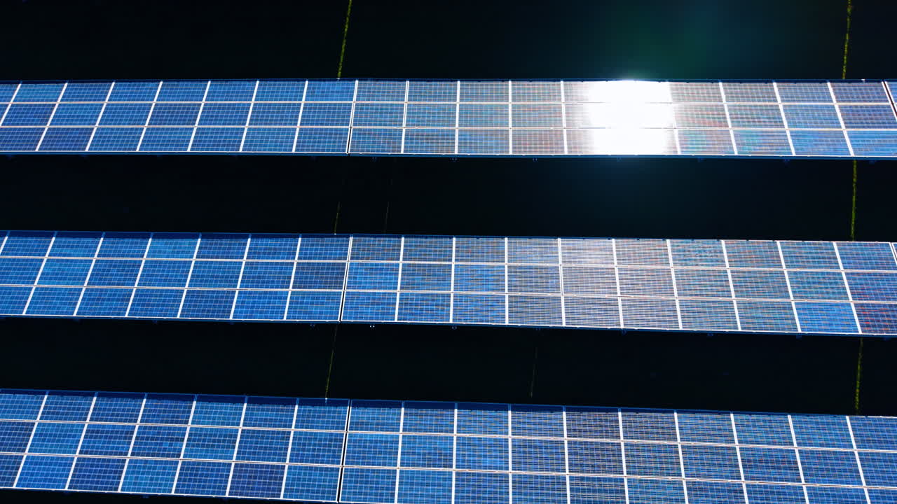 Vista aerea ravvicinata di pannelli solari con riflesso del sole. Vista tecnica di pannelli solari blu con luce solare intensa che si riflette sulla superficie di vetro, tecnologia per l'energia rinnovabile