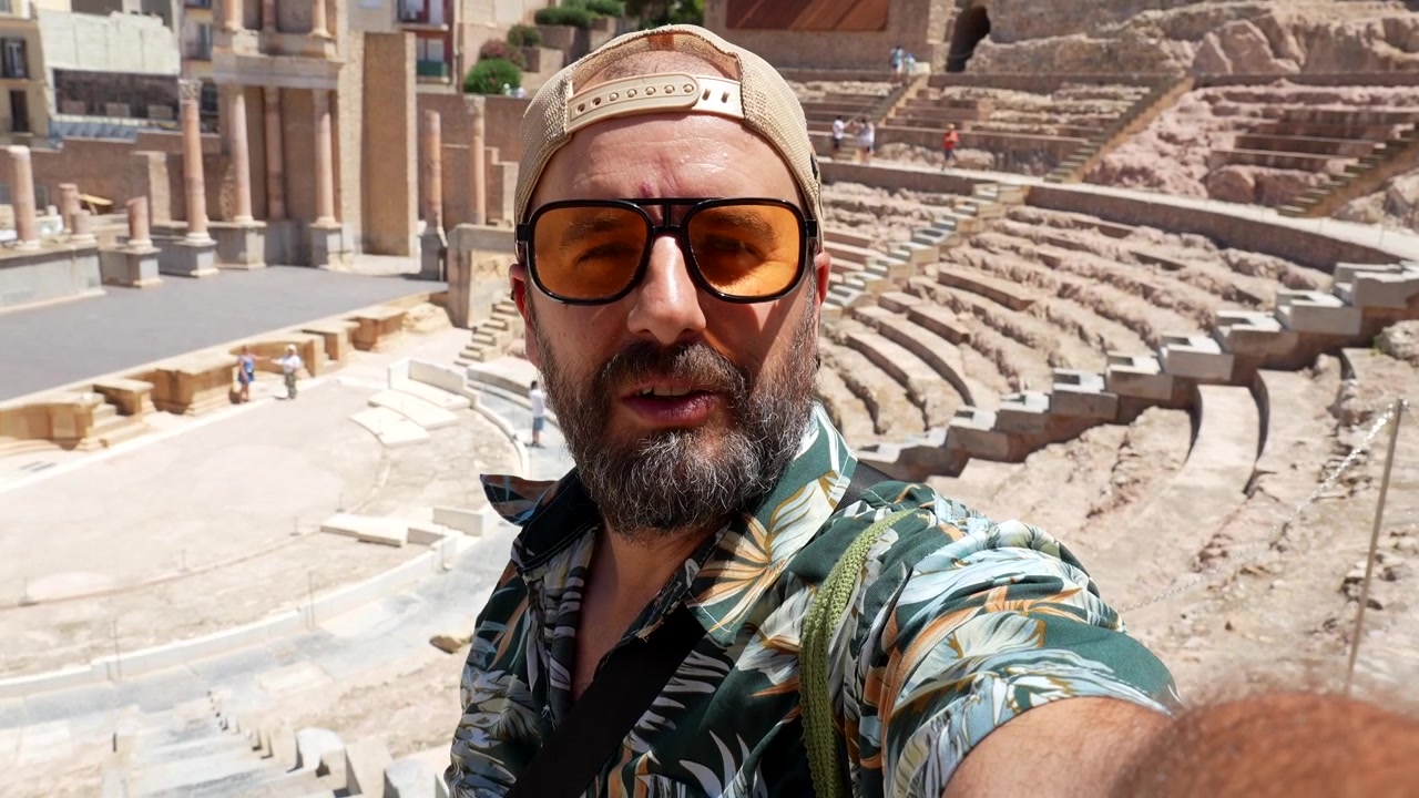 Man filmar sig själv vid ruiner av en antik romersk teater