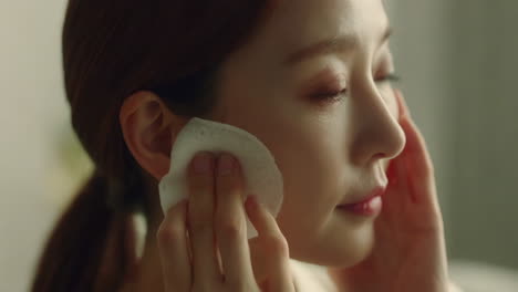 woman applying facial cotton pad