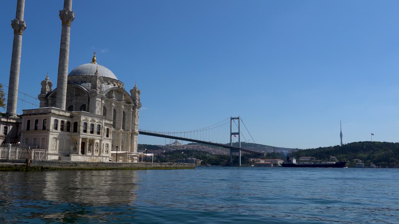 buque de carga que pasa bajo el puente del bósforo con la mezquita ortakoy en primer plano, estambul, turquía