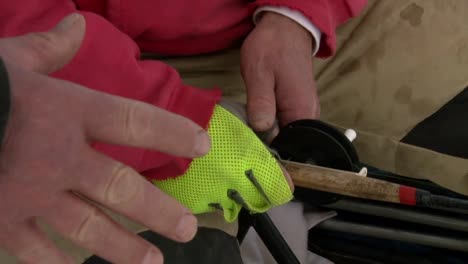 ice fishing while holding a fishing rod and wearing gloves - close up