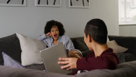 lesbian couple using digital tablet in living room