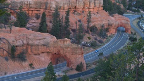 Aerial-view-of-a-car-driving-through-one-of-the-Red-Cayon-road-arches-near-Bryce-Canyon