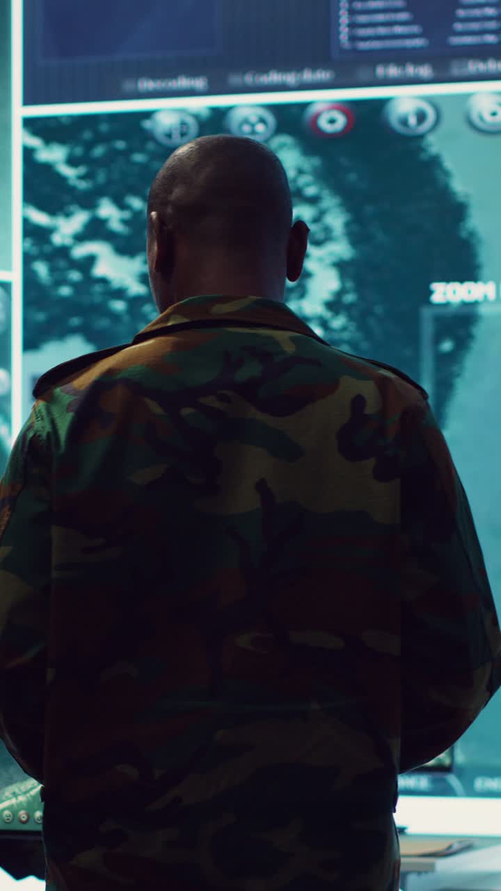 Military Man in Camouflage Observing Surveillance Data on Large Screen