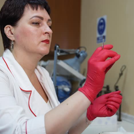adult woman medic works with paints in optics. coloring lenses in different colors with brush. ophthalmologist in latex gloves and brush