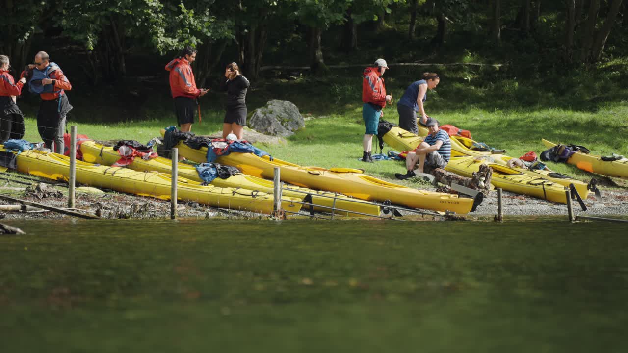 People and kayaks on a sunny lakeshore
