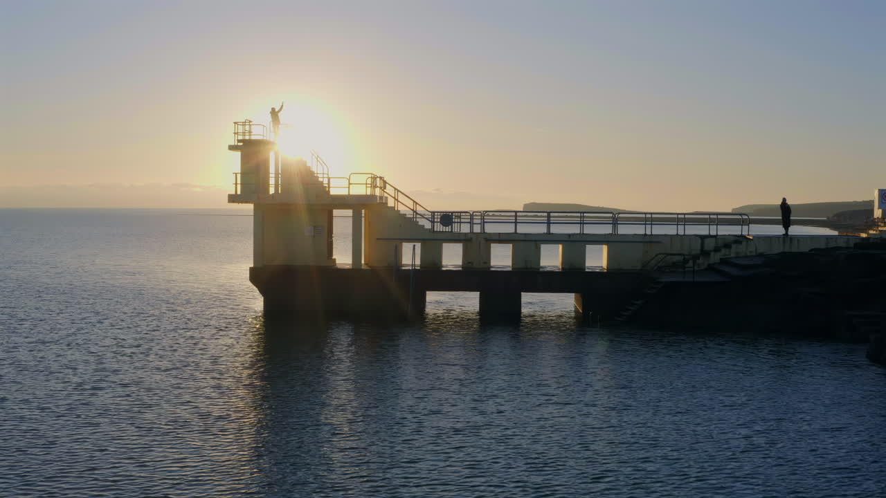 Aerial pan of Blackrock diving board silhouetted at sunset. Galway, Ireland