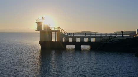 aerial pan of blackrock diving board silhouetted at sunset. galway, ireland