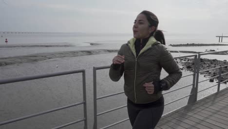 smiling brunette hindu woman running on pier at seaside