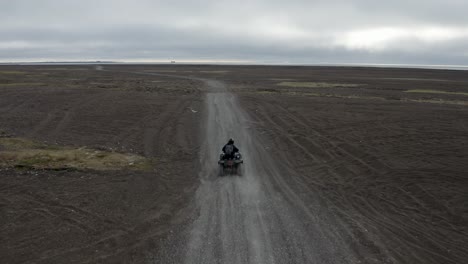 Luftverfolgungsdrohnenaufnahme-Eines-Einsamen-Mannes-Auf-Einem-Geländefahrzeug-Am-Schwarzen-Sandstrand-Am-Nördlichsten-Punkt-Der-Arktischen-Vereinigten-Staaten-In-Der-Nähe-Von-Barrow,-Alaska