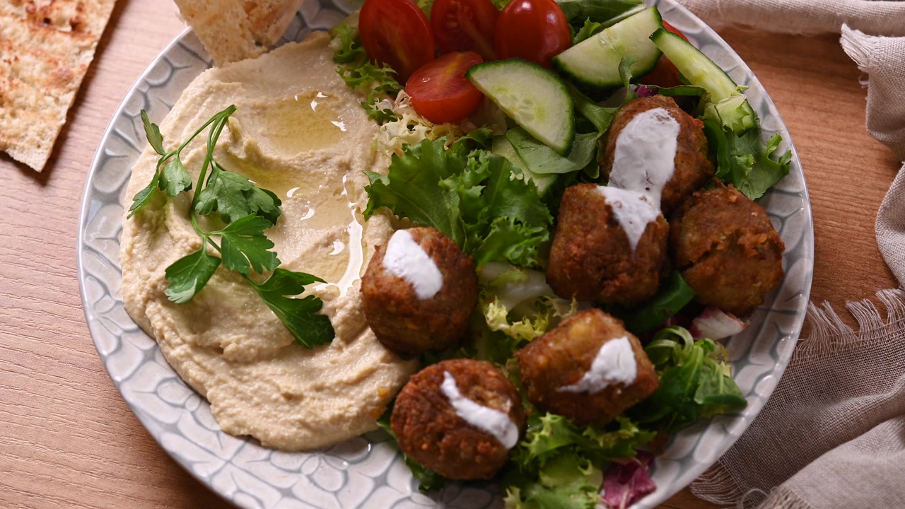 Mano che intinge pane pita nell'hummus cremoso