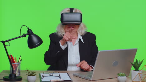 Senior-businesswoman-using-headset-helmet-app-to-play-simulation-game-watching-virtual-reality-video