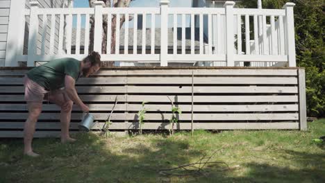 a person is watering growing plants at the backyard of his home