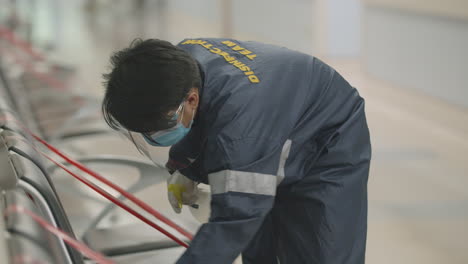 janitor disinfecting public chairs to avoid the spread of coronavirus inside the hospital