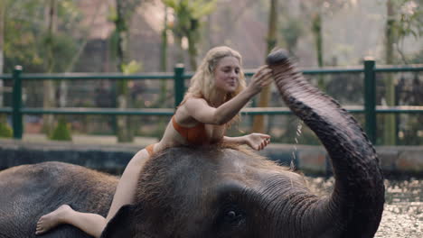 beautiful-woman-riding-elephant-in-zoo-playing-in-pool-spraying-water-female-tourist-having-fun-on-exotic-vacation-in-tropical-forest-sanctuary