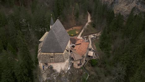 aerial drone top-down orbiting above stunning san romedio sanctuary perched on rock of predaia in trentino