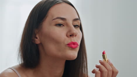 happy girl makeup routine bathroom closeup. woman applying red lipstick visage