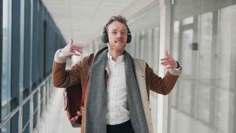 joven elegante bailando con auriculares en el pasillo