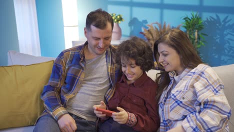 Porträt-Einer-Glücklichen-Familie,-Die-Spaß-Mit-Dem-Smartphone-Auf-Dem-Sofa-Im-Wohnzimmer-Hat.