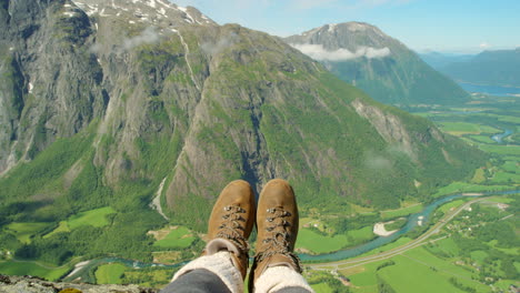 los pies colgando sobre los impresionantes fiordos noruegos