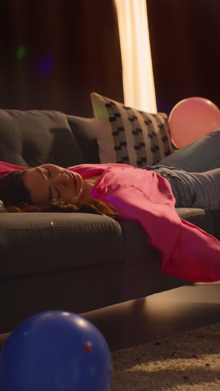 Vertical Video Of Woman Lying Passed Out On Sofa After Drinking Alcohol At House Party Suffering With Hangover