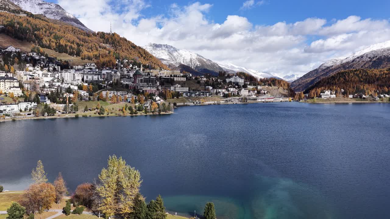 St. Moritz lake in Engadin Graubünden Switzerland with clear water, autumn trees and snowy mountains from drone push forward