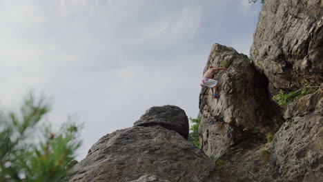 rock climber jumping from ridge to edge, mountain climbing, freeclimbing man, bouldering in rocky environment, adventurous, spectaculair, solo, action shot, static cinematic wide in sunny landscape