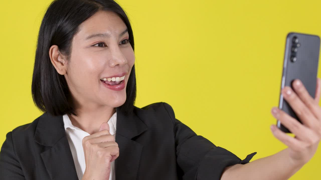 Una sorridente donna d'affari in posa per un allegro selfie, gesti espressivi, illuminazione brillante, vivace sfondo giallo