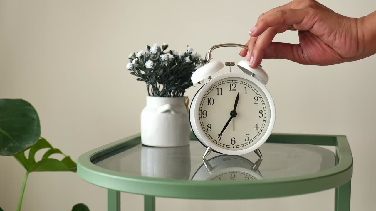 Mano apagando un despertador blanco por la mañana.