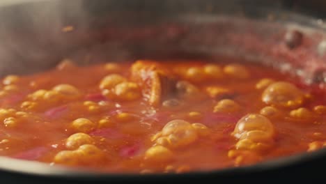 chicken in tomato sauce is boiling on a frying pan with spices. cooking tomato sauce curry with chicken fillet. traditional italian mexican asian dish. high quality studio shot for cafe, restaurant close up.