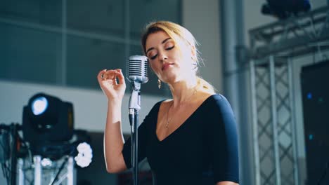 musical star on the stage. attractive woman singer performing a live music into the microphone for special event. slow motion.