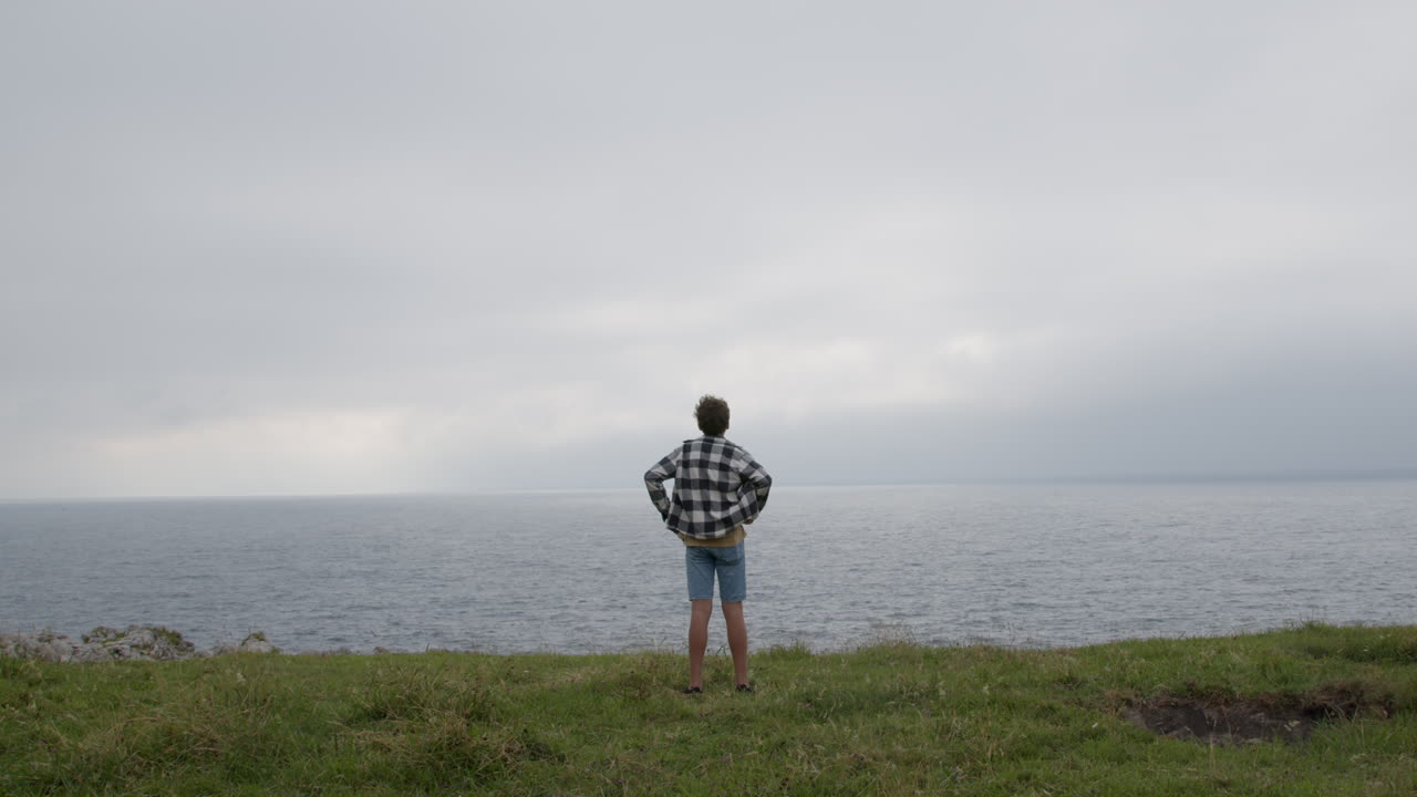 바다를 내려다보는 절벽 위에 서 있는 십대