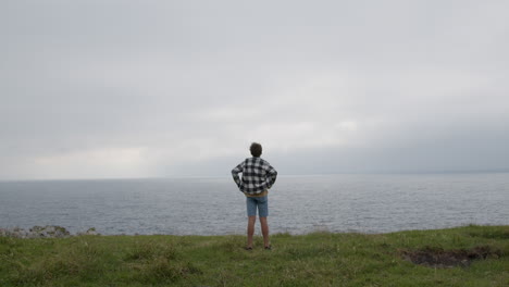 teenager standing on a cliff overlooking the ocean