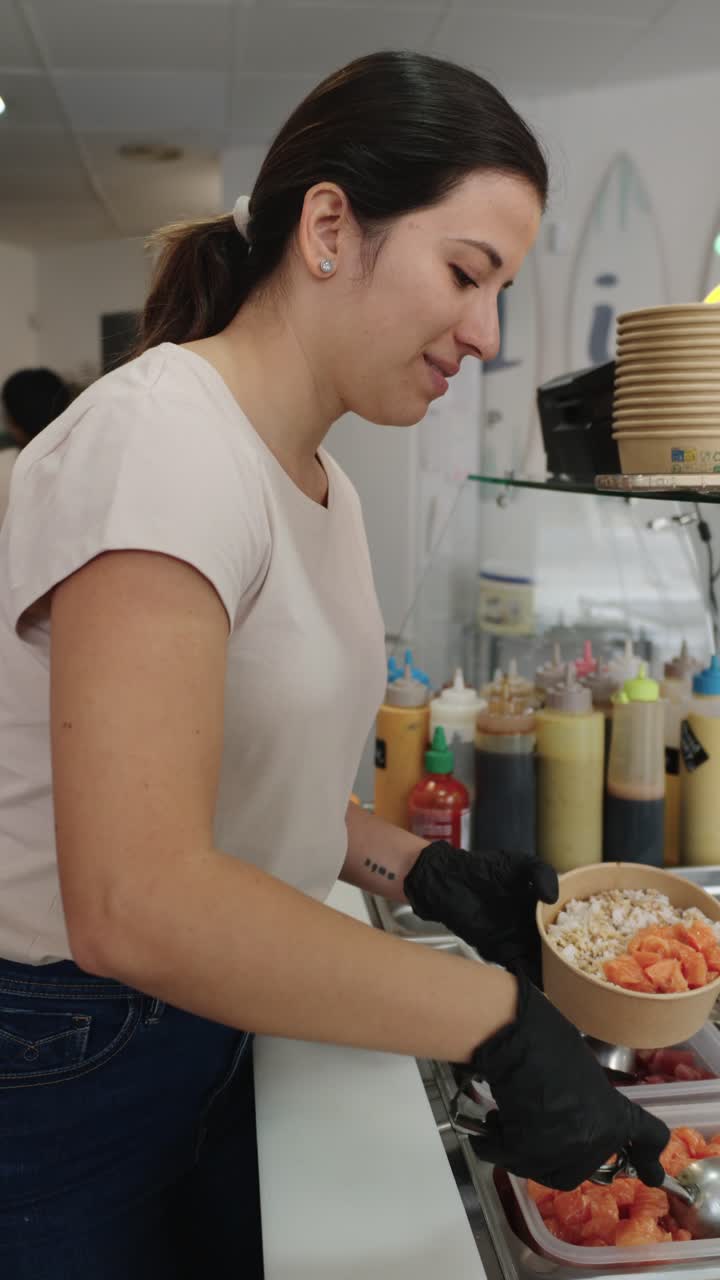 Woman preparing poke bowl in restaurant