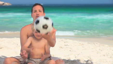 padre e hijo jugando a la pelota en una playa