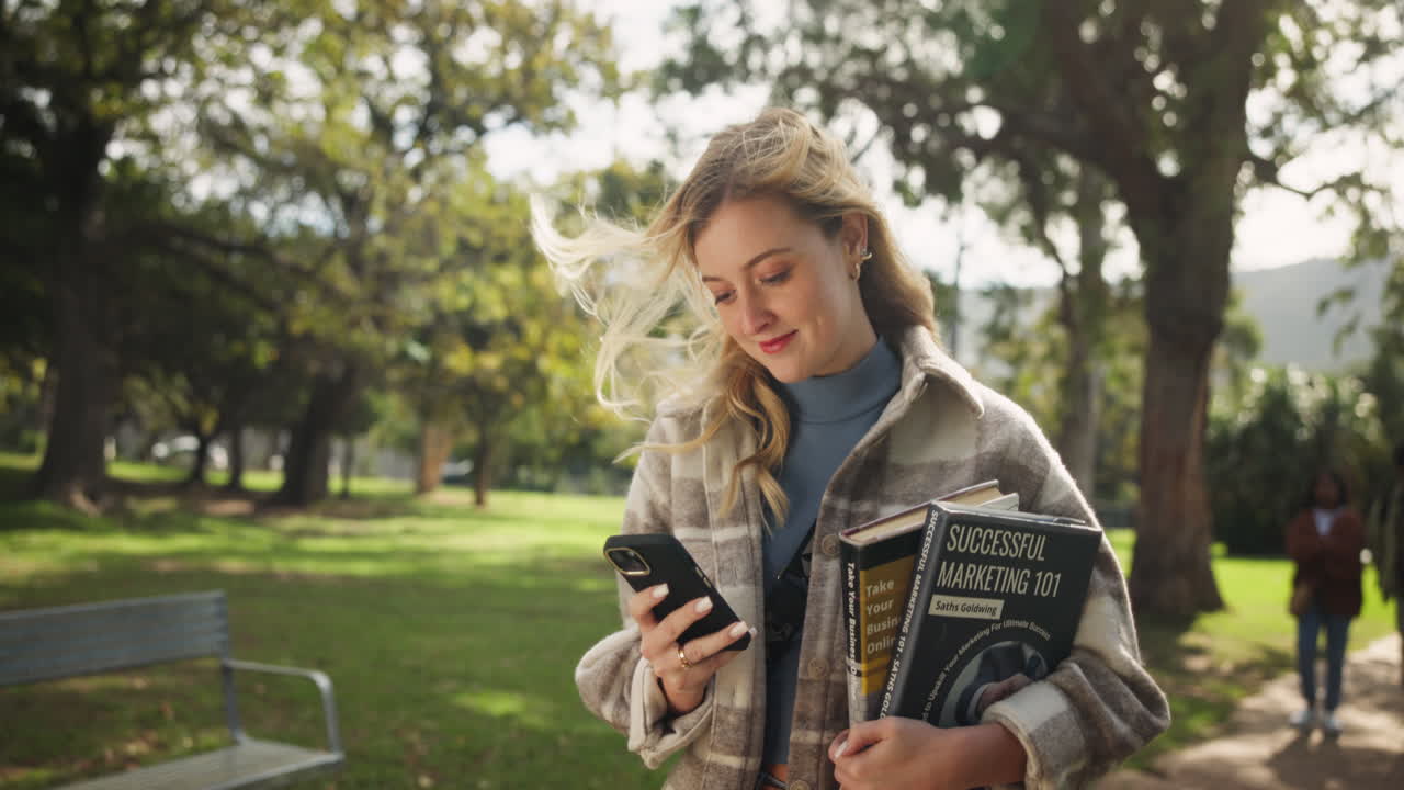 Woman with phone and books in the park