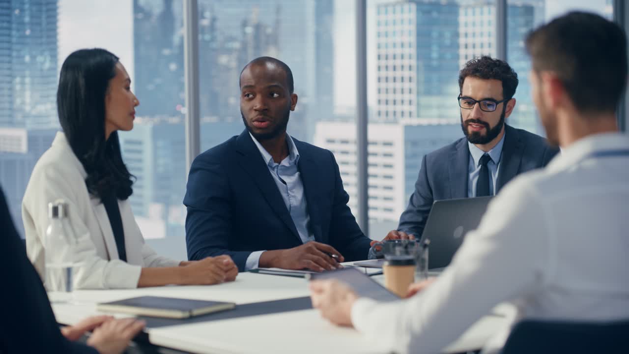Modern Multi-Ethnic Office Conference Room Meeting: Ambitious Motivated Black Businessman Presenting Investment Strategy to Partners, Pitching Investment Strategy. Diverse Team Businesspeople Talk