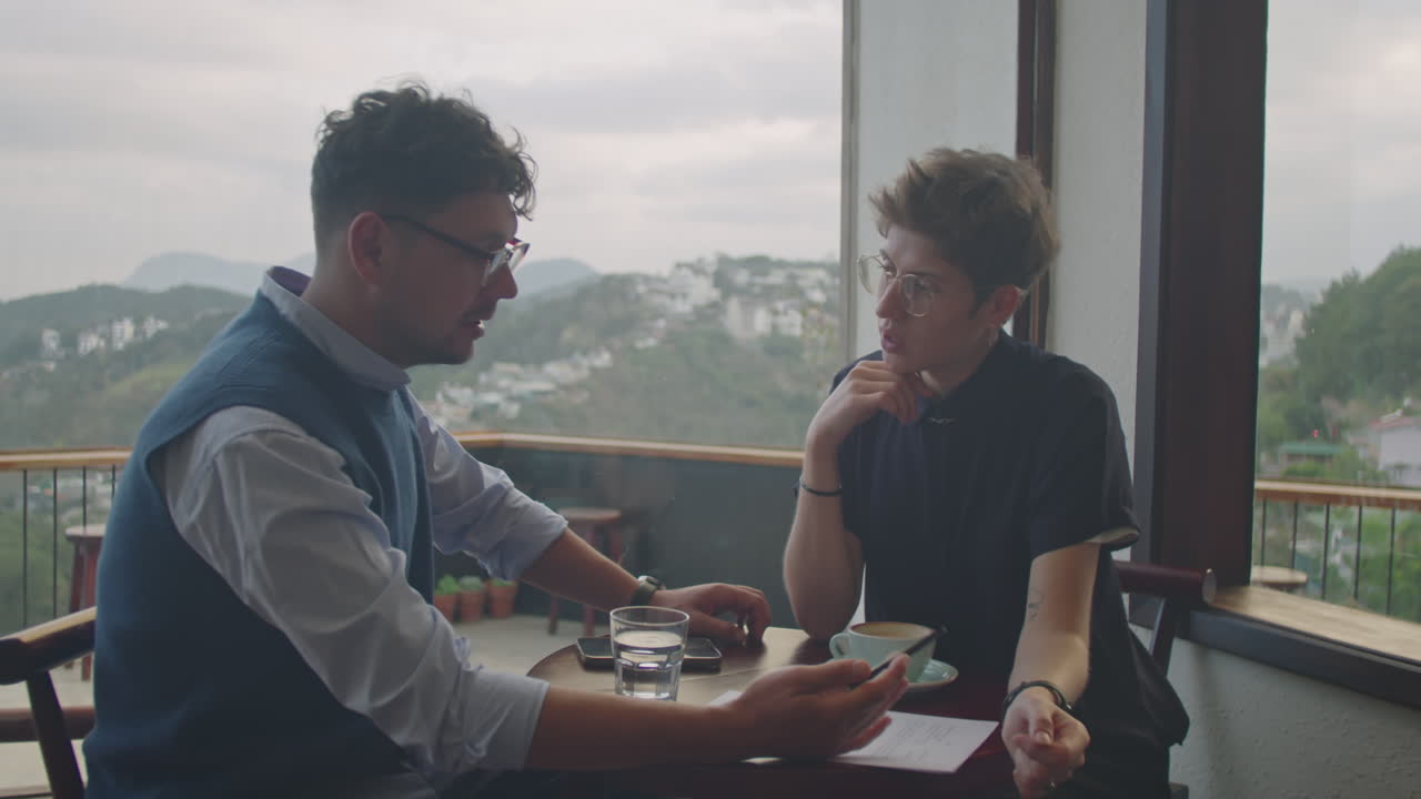 Colleagues Discussing Document in Cafe with Mountain View