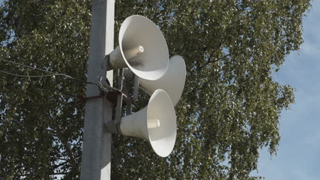 a set of white loudspeakers attached to a pole