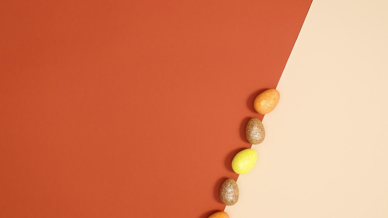 los huevos brillantes de pascua aparecen en línea en el fondo rojo desnudo y de ladrillo.