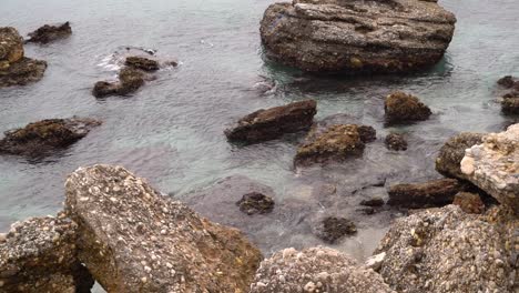 Slow-motion-view-over-shallow-ocean-water-with-rocky-beach