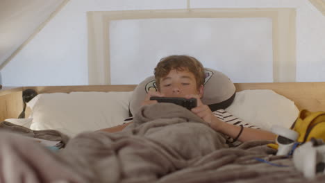 teenager playing games on phone in bed