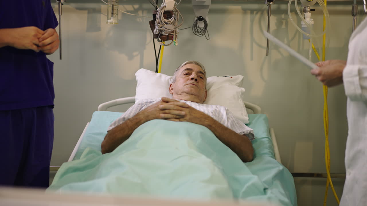 Elderly patient in hospital bed with medical staff attending