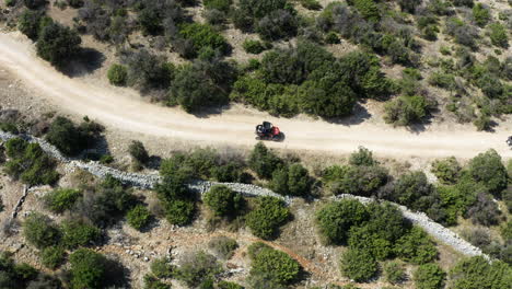 two beach buggy turn corner of small dry dusty road, drone shot